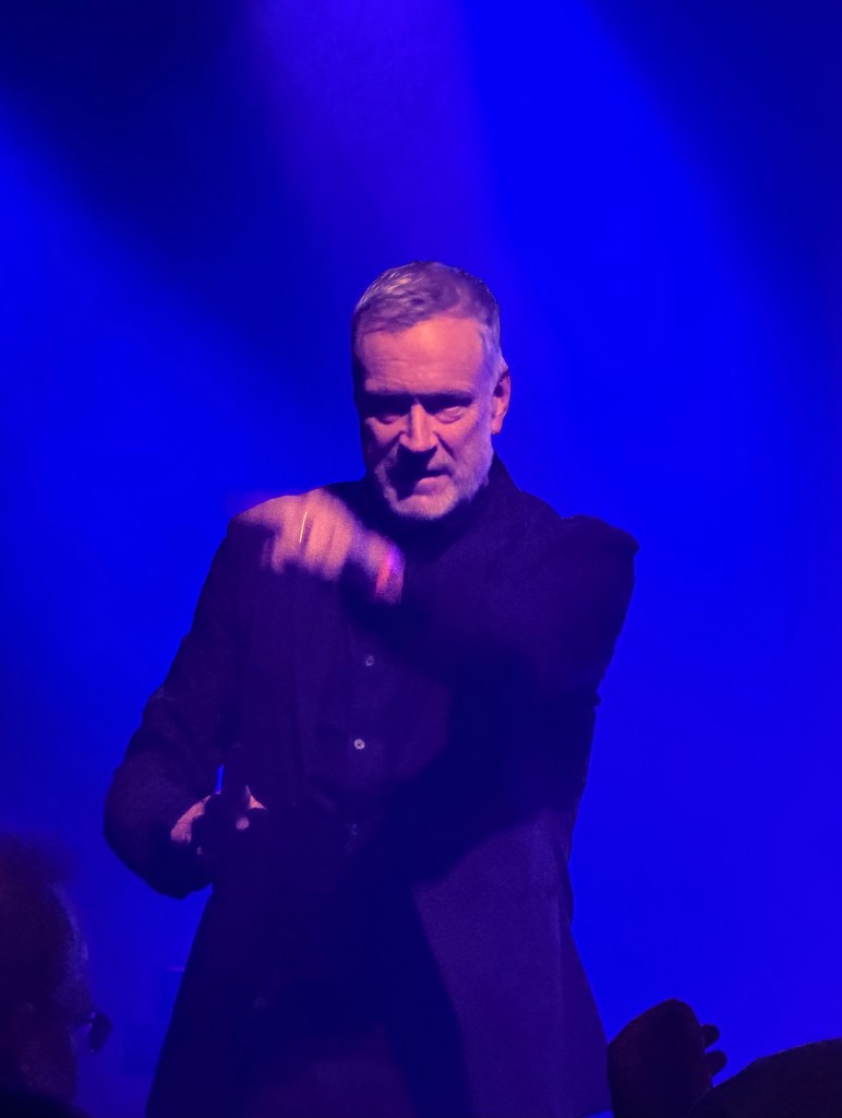 A performer engaging with the audience under blue stage lights.