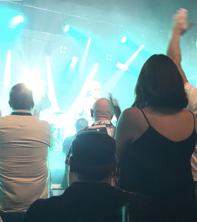 Audience watching a live performance with stage lights illuminating the scene.